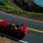 Person driving convertible on a coastal highway in California.